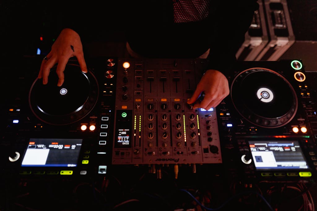 Close-up of a DJ using a sound mixer and audio equipment during a performance.